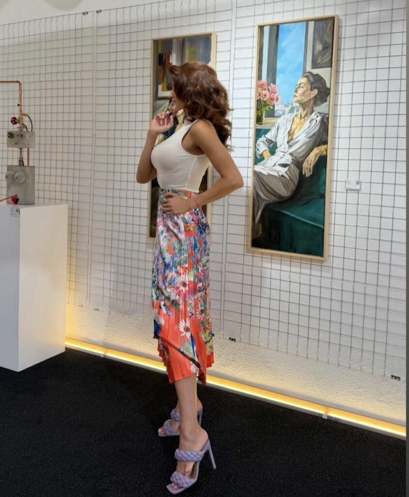 A visitor in front of paintings and a sculpture.